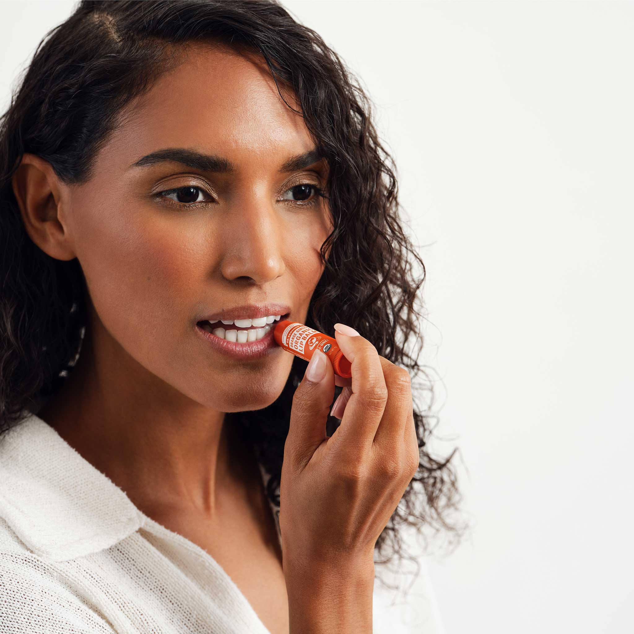Person applying Dr. Bronner's Orange Ginger Organic Lip Balm