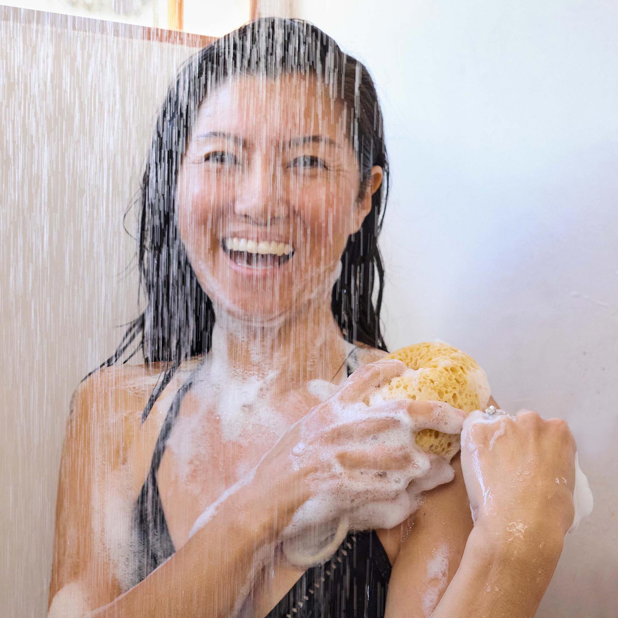 Person showering with Dr. Bronner's Tea Tree Pure-Castile Liquid Soap