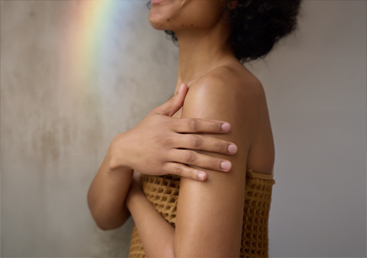 A person wrapped in a brown waffle towel smoothing lotion over their shoulder and upper arm, the body application photograph from Dr. Bronner's Peppermint Organic Lotion page.