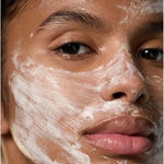 Close-up of a woman wearing Dr Hauschka Hydrating Cream Mask 30ml in visible white brush strokes across her forehead, cheeks, nose and chin.