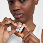 Model holding an open jar of Dr Hauschka Lip Balm between both hands.