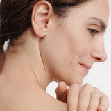 Woman smoothing a white streak of Dr Hauschka Regenerating Body Cream 150ml across her bare shoulder with her fingertips.