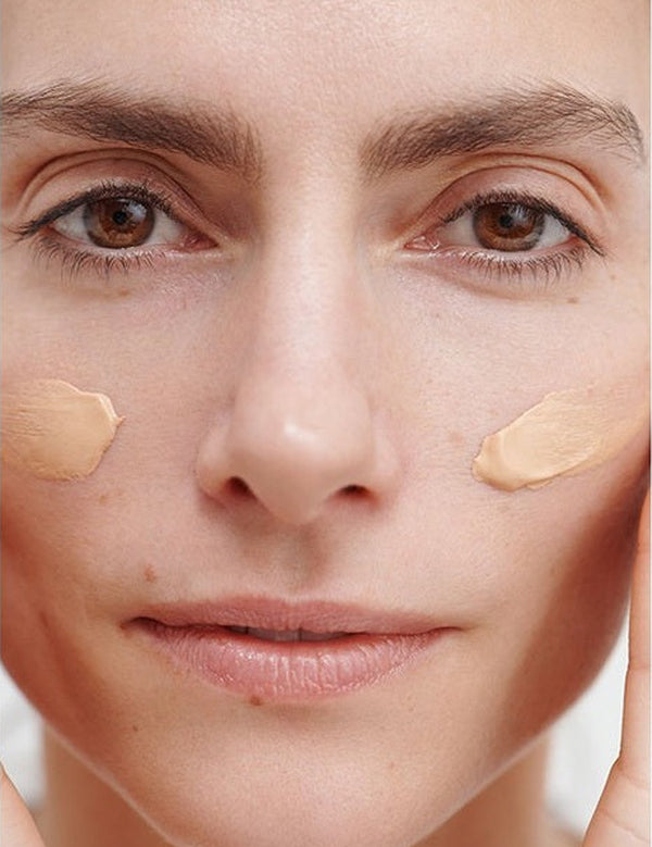 Model wearing two cheek swatches of Dr Hauschka Regenerating Day Cream Complexion Tinted 40ml before blending.