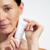 Model holding a tube of Dr Hauschka Regenerating Day Cream 40ml beside her face.