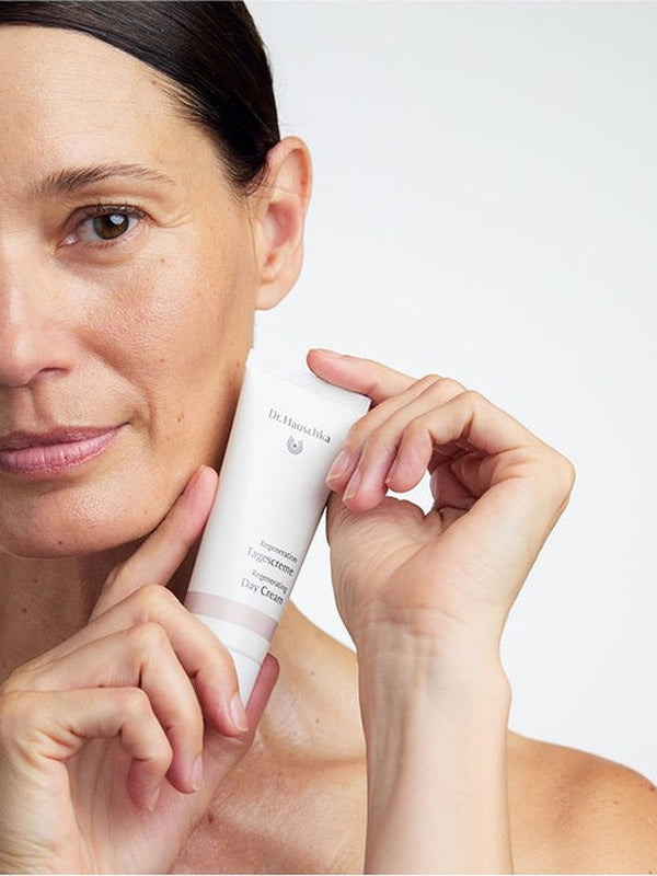 Model holding a tube of Dr Hauschka Regenerating Day Cream 40ml beside her face.