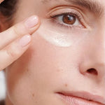 Close-up of a woman smoothing Dr Hauschka Regenerating Eye Cream 15ml beneath her eye with two fingertips.