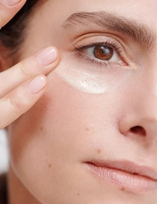 Close-up of a woman smoothing Dr Hauschka Regenerating Eye Cream 15ml beneath her eye with two fingertips.