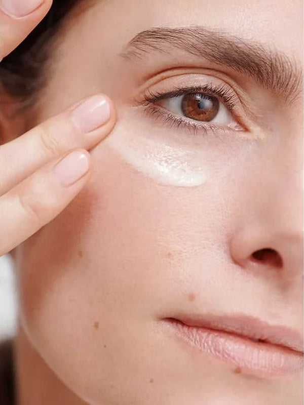 Close-up of a woman smoothing Dr Hauschka Regenerating Eye Cream 15ml beneath her eye with two fingertips.