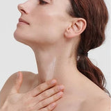 Woman massaging Dr Hauschka Regenerating Neck and Décolleté Cream 40ml into the front of her neck with her chin gently raised.