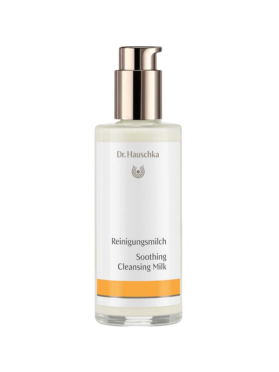Dr Hauschka Soothing Cleansing Milk in a clear bottle containing ivory lotion, with a reflective metal pump and white label with a golden-yellow band.