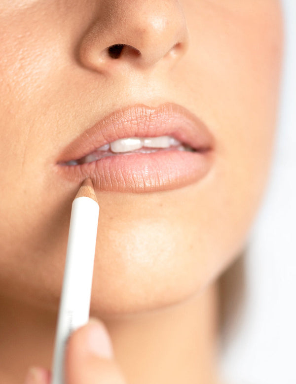 Close-up of a model applying an Ere Perez Acai Lip Pencil to the lower lip for softly defined natural colour.