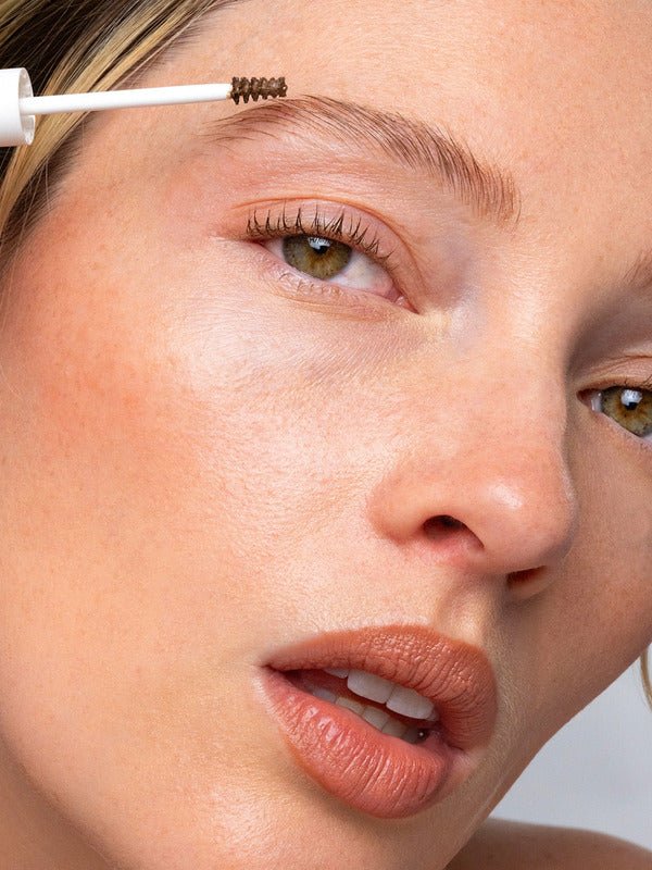 Close-up of a model applying Ere Perez Argan Brow Hero to shape and groom the eyebrow.