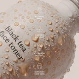 Water droplets on an Ere Perez Black Tea Face Toner bottle beneath icons labelled alcohol free, barrier support, botanical actives and sensitive skin safe.