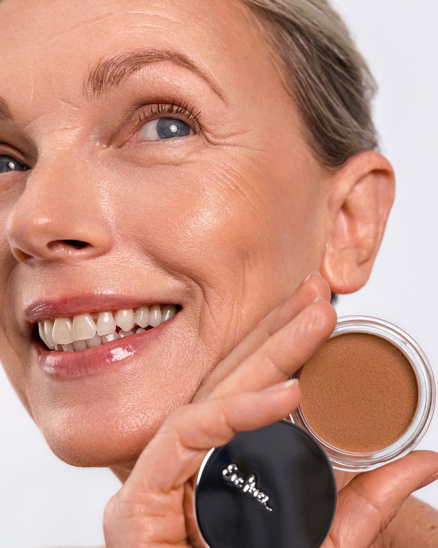 Model wearing Ere Perez Cacao Bronzing Pot in Playa and holding the open pot