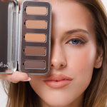 Model holding the open Ere Perez Element Matte Chamomile Eye Palette beside her face, with five neutral shades visible and softly blended brown eyeshadow on the exposed eye.