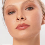 Close-up of a model wearing the earthy brown Oak shade from the Ere Perez Element Matte palette, blended over the eyelids and beneath the lower lashes. An Oak swatch appears at the lower left.