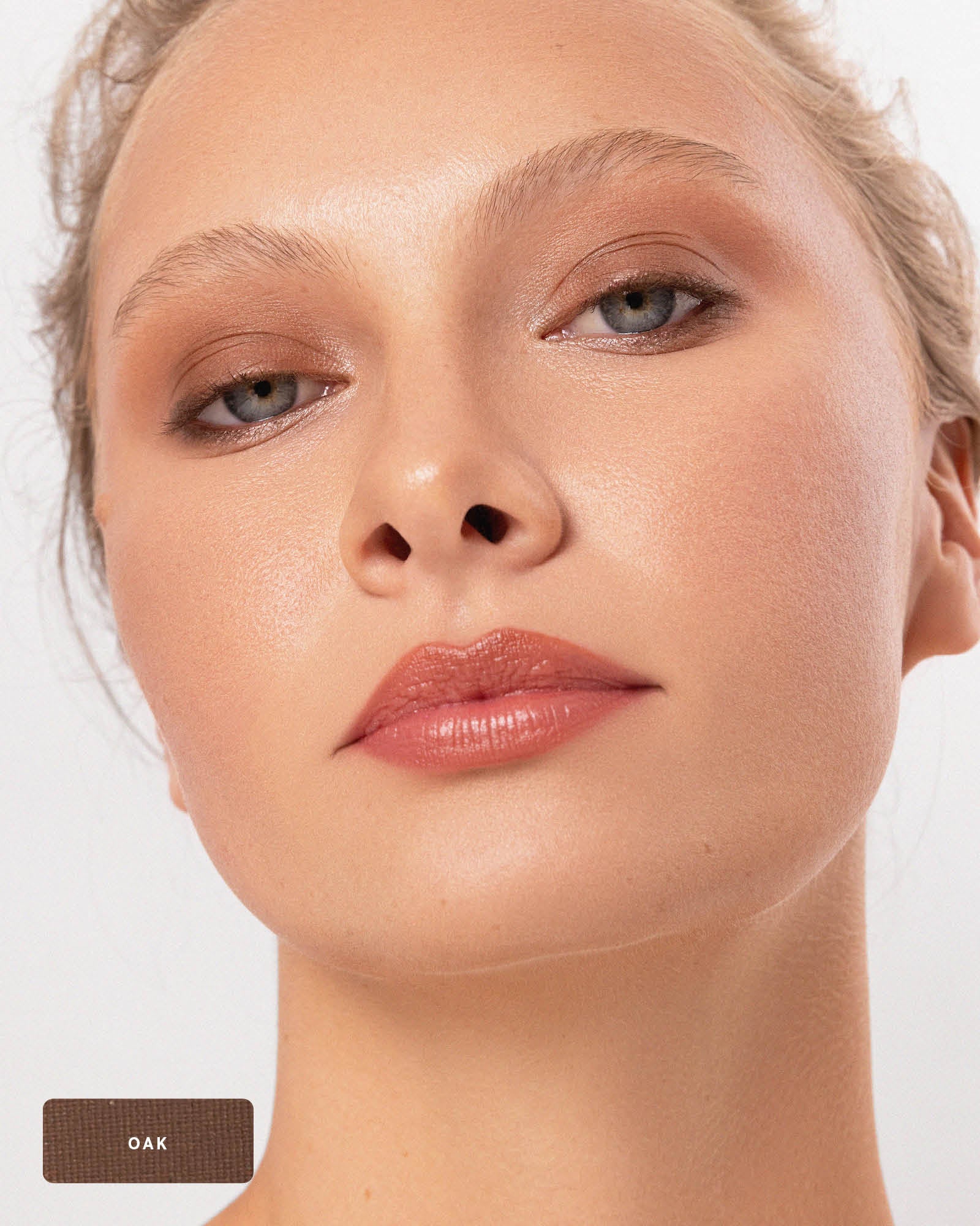 Close-up of a model wearing the earthy brown Oak shade from the Ere Perez Element Matte palette, blended over the eyelids and beneath the lower lashes. An Oak swatch appears at the lower left.