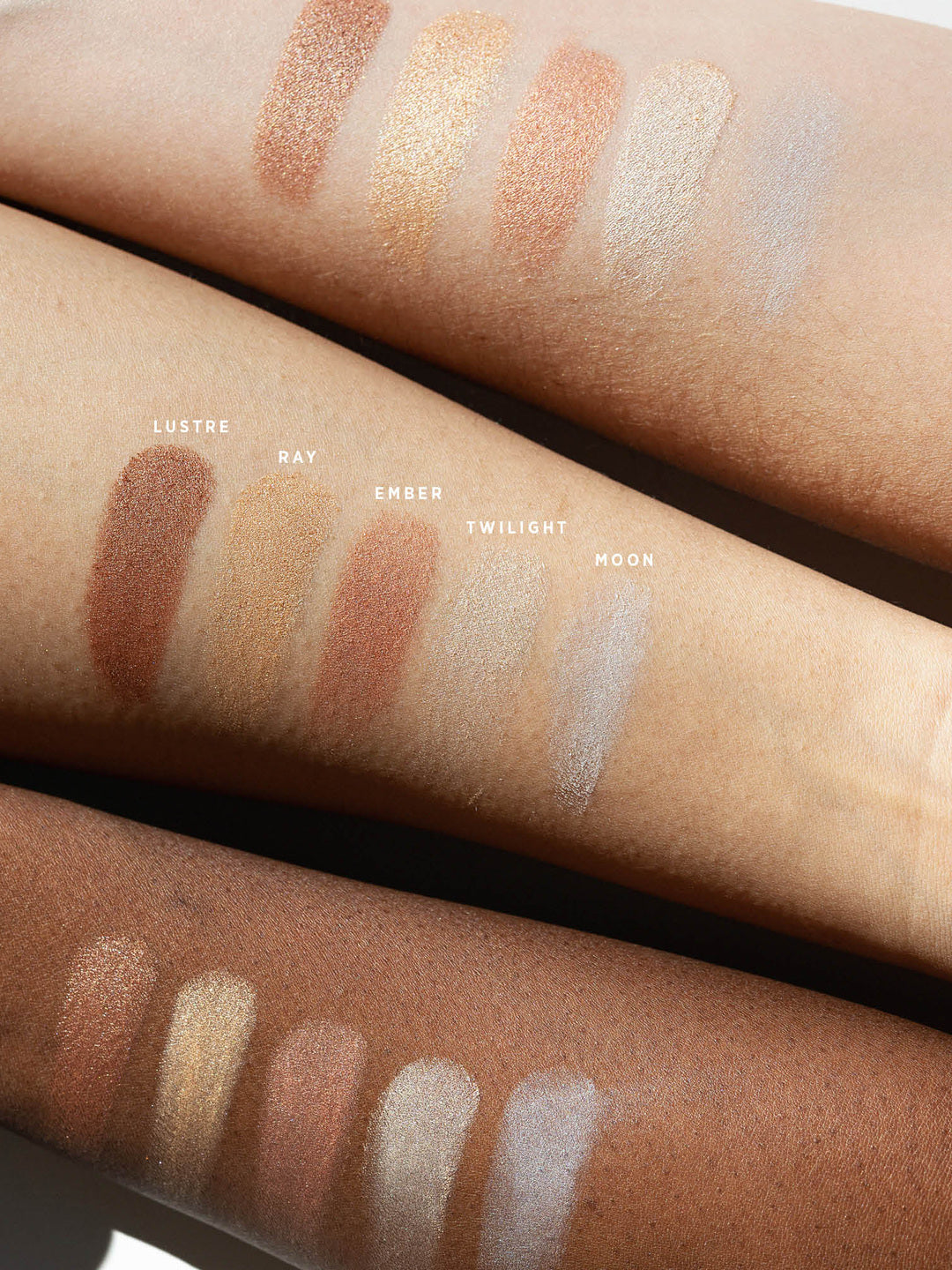 Ere Perez Light Shimmer eyeshadow swatches on three forearms with light, medium and deep skin tones. Lustre, Ray, Ember, Twilight and Moon show bronze, gold, rosy copper, pearl and cool silver finishes.
