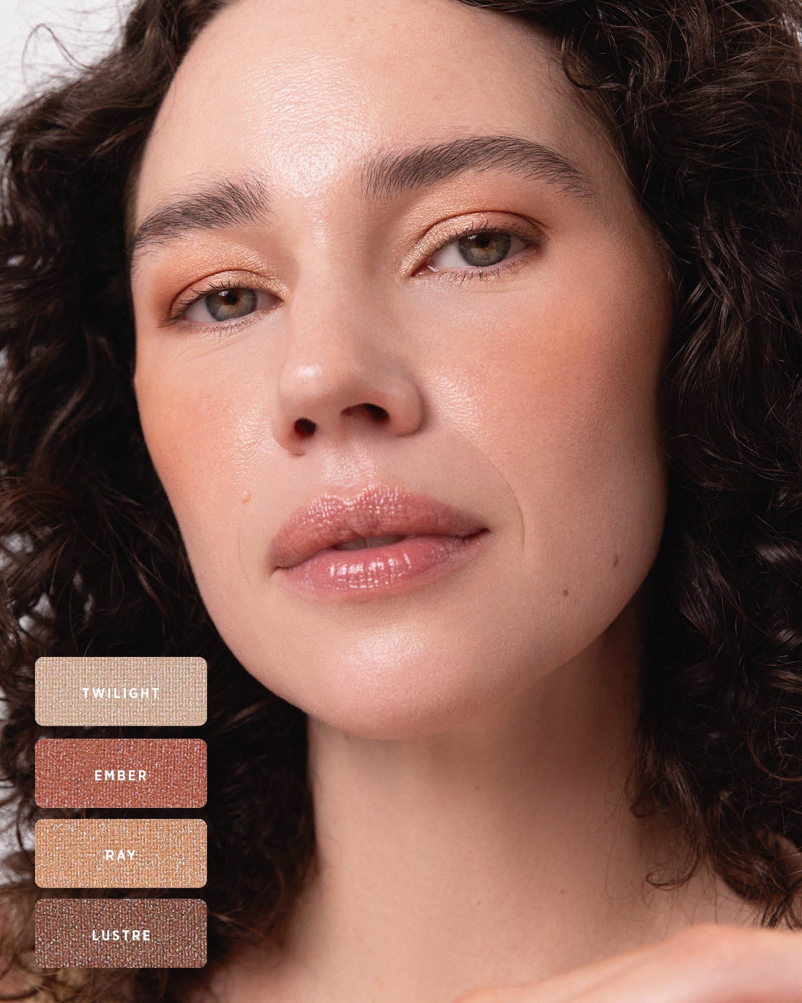 Curly-haired model wearing warm peach and bronze shimmer on the eyelids. Swatches identify Twilight, Ember, Ray and Lustre from the Ere Perez Light Shimmer palette.