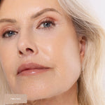 Close-up of a silver-haired model wearing softly blended rose-bronze shimmer on the eyelids. Twilight and Lustre swatches identify the Ere Perez Light Shimmer palette shades used.