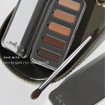 Ere Perez Eco Vegan Eye Duo Brush resting diagonally across a metal tray beside an open Element Matte Chamomile Eye Palette, with both brush heads visible. Text reads 'Pair with eco vegan eye duo brush'.