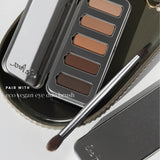 Ere Perez Eco Vegan Eye Duo Brush resting diagonally across a metal tray beside an open Element Matte Chamomile Eye Palette, with both brush heads visible. Text reads 'Pair with eco vegan eye duo brush'.