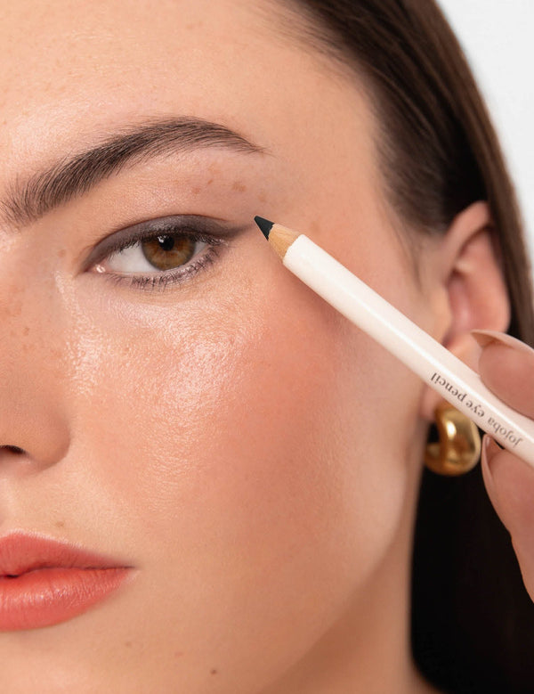 Model applying an Ere Perez Jojoba Eye Pencil along the outer upper lash line.