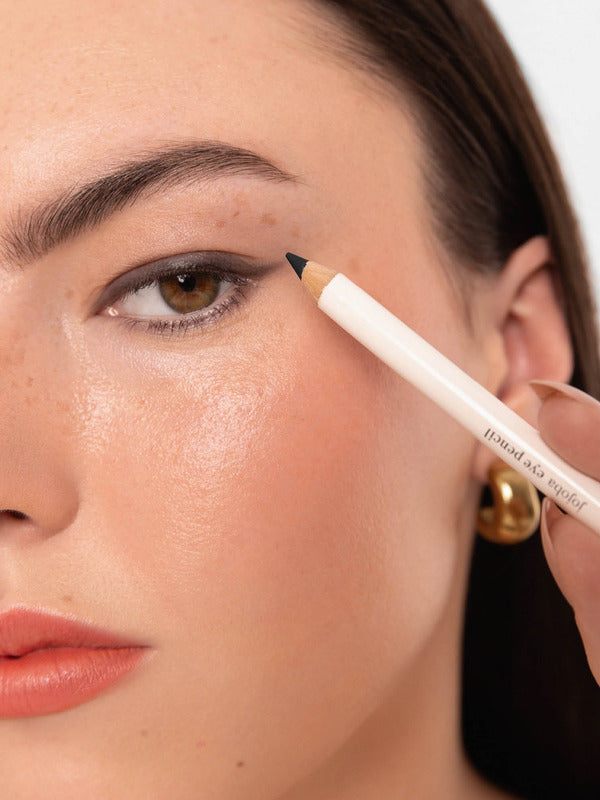 Model applying an Ere Perez Jojoba Eye Pencil along the outer upper lash line.
