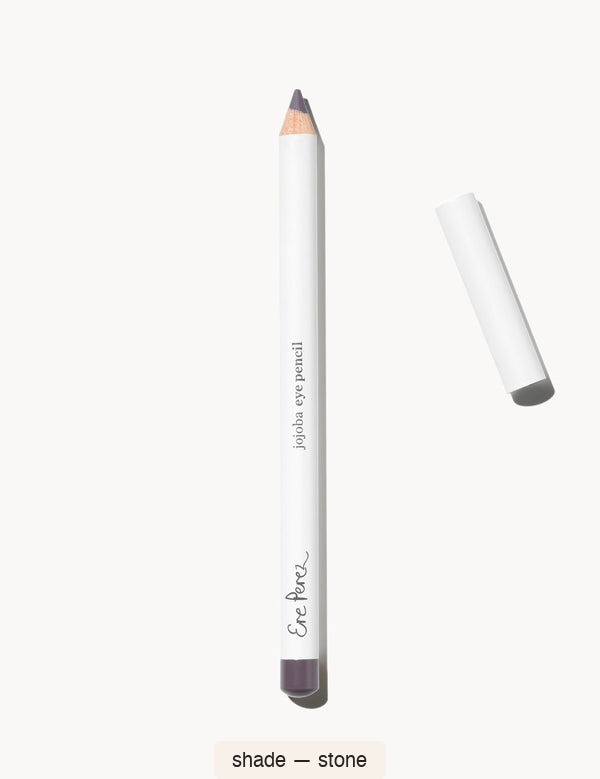 White Ere Perez Jojoba Eye Pencil in Stone, with an exposed muted violet-grey tip, a matching end cap and its white lid beside it; the shade name appears below.