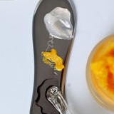 Ere Perez Steel Face Tool gua sha with dollops of skincare on its polished steel surface