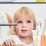 Child brushing teeth beside Davids Orange and Vanilla Toothpaste