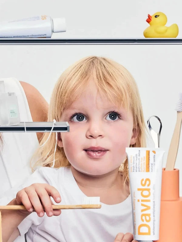 Child brushing teeth beside Davids Orange and Vanilla Toothpaste