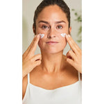 Woman applying cream to her face with both hands