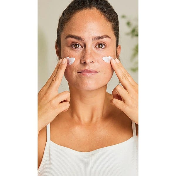 Woman applying cream to her face with both hands
