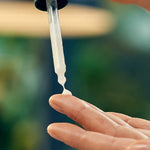 Firming face serum pipette being squeezed onto a finger before application.