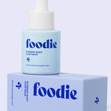 Vanessa Megan Foodie Blueberry Burst Glow Serum 20ml blue dropper bottle standing on its matching lilac carton against a lilac background.