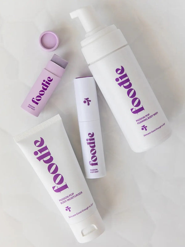 Vanessa Megan Foodie Passion Pop four-piece Body Bundle: foaming body wash, body moisturiser, face and body mist, and lip balm arranged on softly folded white fabric, with the lip balm open.