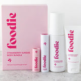 Vanessa Megan Foodie Strawberry Sundae four-piece Body Bundle: foaming body wash, body moisturiser, face and body mist, and lip balm standing beside the pink gift box on a pale stone surface.