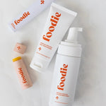 Vanessa Megan Foodie Tropical Pavlova four-piece Body Bundle: foaming body wash, body moisturiser, face and body mist, and lip balm arranged on softly folded white fabric, with the lip balm open.