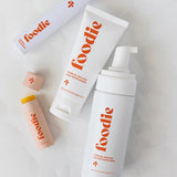 Vanessa Megan Foodie Tropical Pavlova four-piece Body Bundle: foaming body wash, body moisturiser, face and body mist, and lip balm arranged on softly folded white fabric, with the lip balm open.