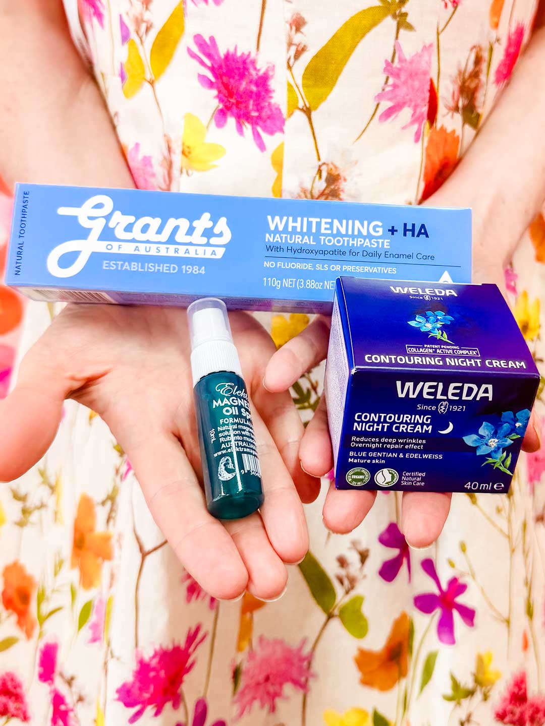 A person in a colorful floral dress holds the FREE Sample Box with Orders $149+—auto added to your order—for a touch of radiant self-care.