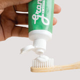 Grants Mild Mint toothpaste being squeezed onto a bamboo toothbrush