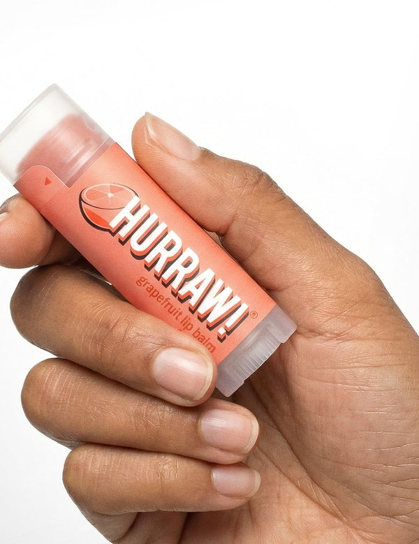 Hand holding Hurraw! Organic Lip Balm - Grapefruit 4.8g