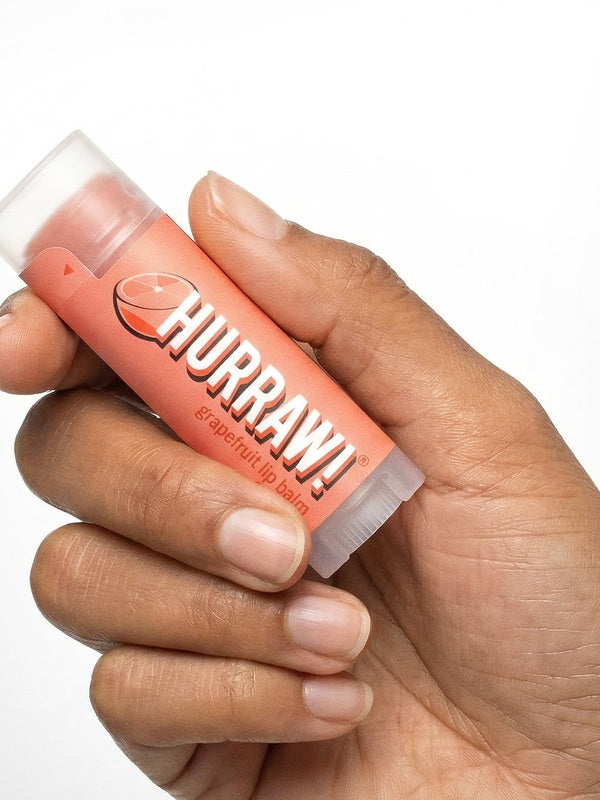 Hand holding Hurraw! Organic Lip Balm - Grapefruit 4.8g