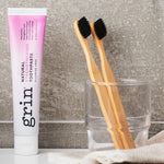 Grin Strengthening Toothpaste with bamboo toothbrushes in a bathroom