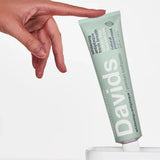 Hand reaching for Davids Whitening and Antiplaque Peppermint Toothpaste
