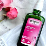Weleda Harmonising Wild Rose Body Oil styled beside pink roses