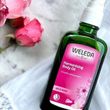 Weleda Harmonising Wild Rose Body Oil styled beside pink roses