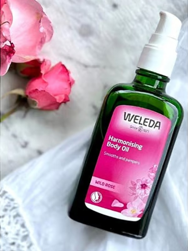 Weleda Harmonising Wild Rose Body Oil styled beside pink roses