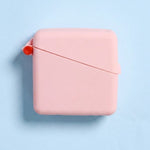 Closed pale pink Hello Caddy case on a light blue background, with rounded corners, a diagonal seam across the front and a small coral loop at the left.
